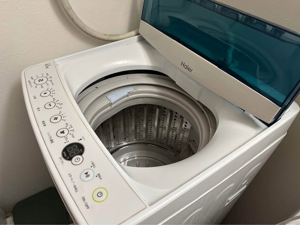Haier top-loading washing machine with the lid open and the control panel clearly visible. The machine appears to be powered off, and the user may be experiencing issues with the power button